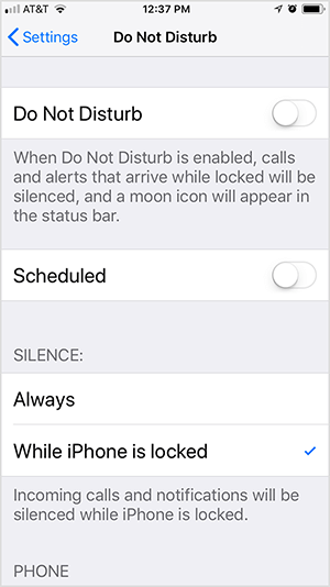 Dit is een screenshot van de iOS Do Not Disturb-instellingen. De eerste optie is om Niet storen in of uit te schakelen. In deze schermafbeelding is de instelling uitgeschakeld. Onder de instelling staat de tekst “Wanneer Niet storen is ingeschakeld, worden oproepen en waarschuwingen die binnenkomen terwijl ze vergrendeld zijn, ook weergegeven gedempt, en een maanpictogram verschijnt in de statusbalk. " Onder deze optie staat de geplande optie, die is omgeschakeld uit. Vervolgens verschijnen er twee opties voor Stilte: Altijd of Terwijl de iPhone is vergrendeld. In deze schermafbeelding is Terwijl iPhone vergrendeld is geselecteerd en de volgende tekst verschijnt "Inkomende oproepen en meldingen zijn het zwijgen opgelegd terwijl de iPhone is vergrendeld. " Todd Bergin zet 