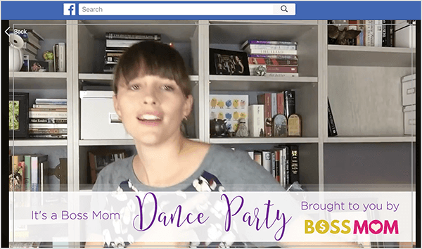 Dit is een screenshot van Dana Malstaff die danst in een Facebook-video die ze heeft gemaakt om een ​​mijlpaal in haar Facebook-groep te vieren. Dana is een blanke vrouw afgebeeld vanaf de kist voor een witte boekenkast met boeken en witte archiefdozen. Haar haar is donkerbruin met pony en de rest is naar achteren getrokken in een paardenstaart. Een banner onder aan de video zegt: "Het is een Boss Mom Dance Party, aangeboden door Boss Mom."